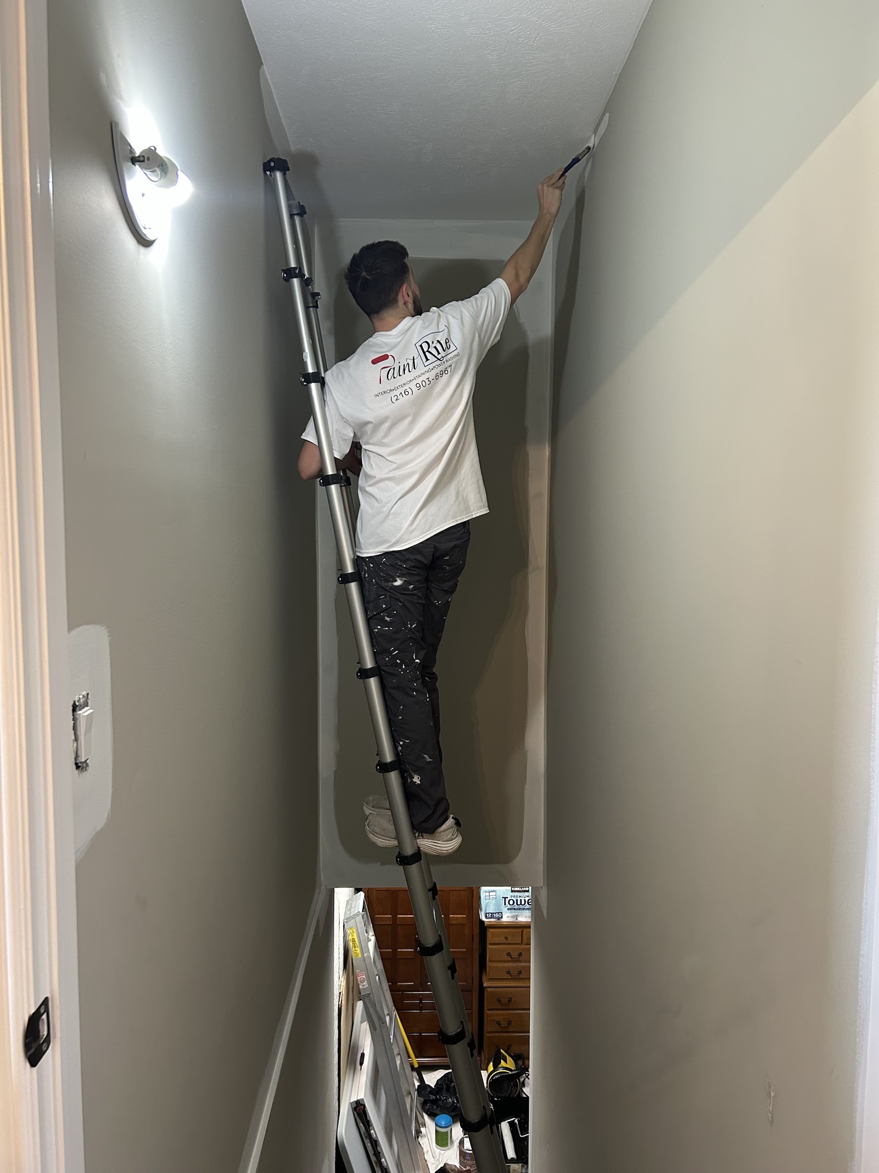 PaintRite painter preparing a tall interior wall